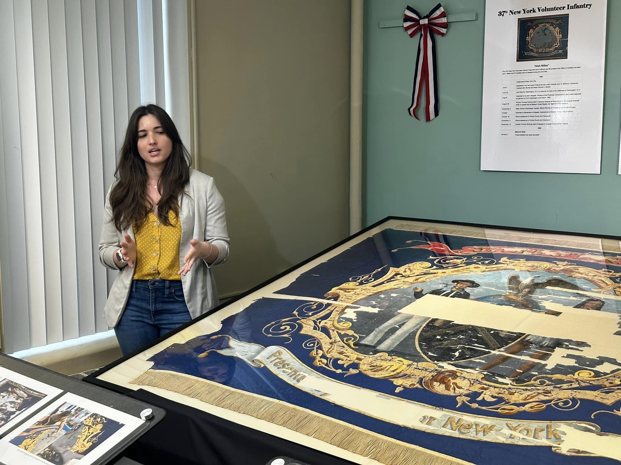 Katya Zinsli, now working at the Smithsonian, speaks next to the 37th NY regimental flag she helped restore.